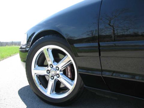 2003 Mercury Marauder - Close-up of a black 2003 Mercury Marauder's front wheel and fender, showing a chrome wheel and Wilwood brake caliper.
