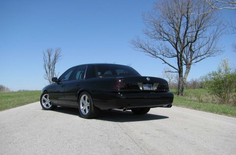 2003 Mercury Marauder - Rear view of a black 2003 Mercury Marauder on a country road under a clear blue sky.
