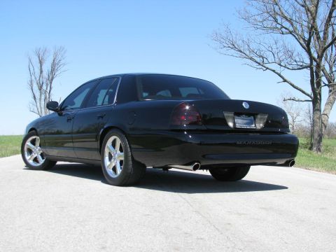 2003 Mercury Marauder - A black 2003 Mercury Marauder sedan is parked on a paved surface under a clear blue sky.