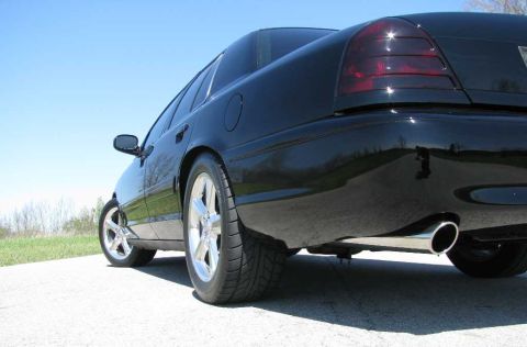 2003 Mercury Marauder - The rear of a black sedan is shown from a low angle, with a bright blue sky overhead.