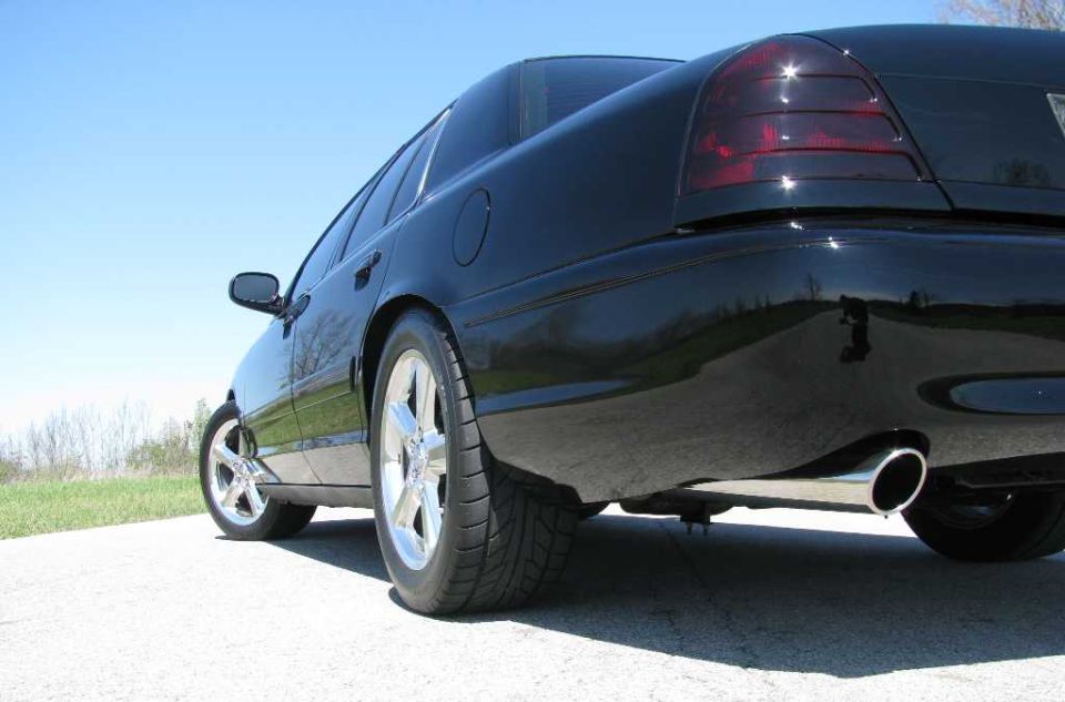 Black sedan's rear quarter panel and tail light, with chrome exhaust tip