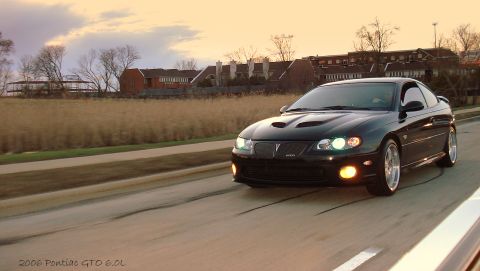 1998 Ford Taurus - Black 2006 Pontiac GTO driving on a road during sunset.