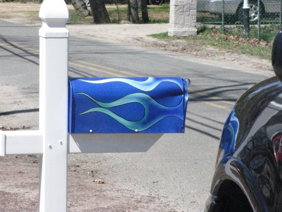 blue mailbox with light blue and white flame graphics, next to a car fender with matching graphics