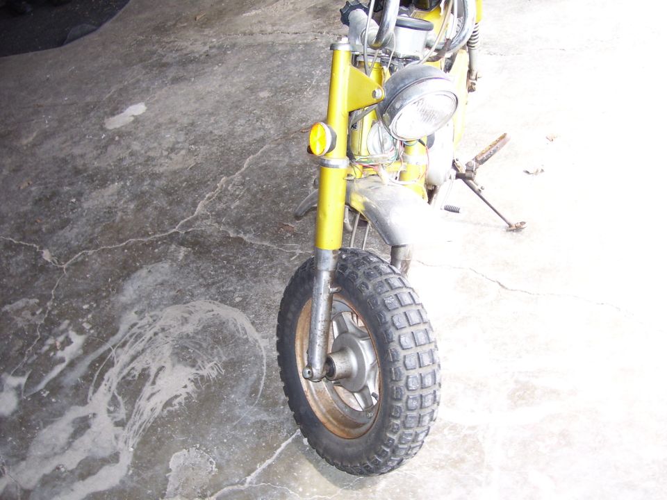 Yellow motorcycle front wheel and fender, parked on concrete