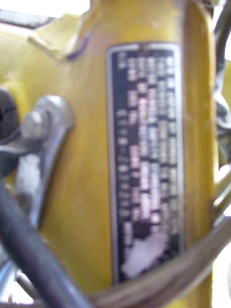Yellow motorcycle frame with a black data plate showing text