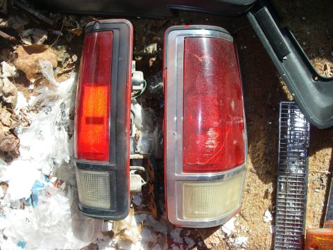 1978 Ford Bronco - Two vehicle tail lights are shown, one with a black bezel and the other with a chrome bezel.