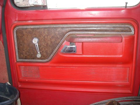 1978 Ford Bronco - Interior door panel of a 1978 Ford Bronco, red vinyl and wood grain accents.