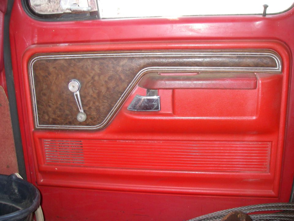 1978 Ford Bronco interior door panel, red with wood grain trim, chrome handle, and speaker grille