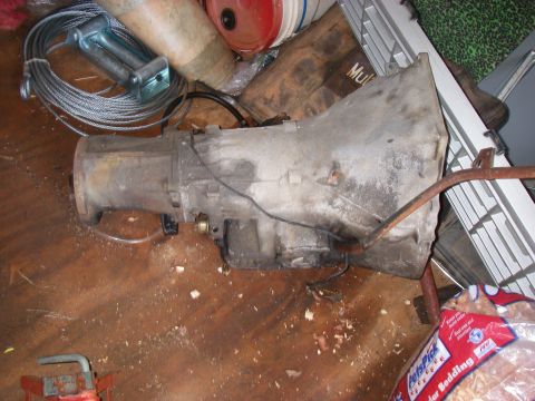 1978 Ford Bronco - An automatic transmission part is shown in a cluttered environment with various items around it.
