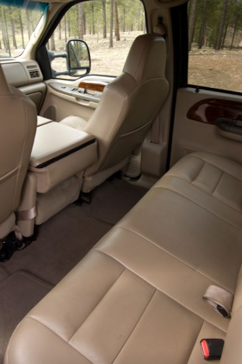 2003 Ford F-350 - The interior of a truck is shown, tan leather seats and a view of trees through the windows.