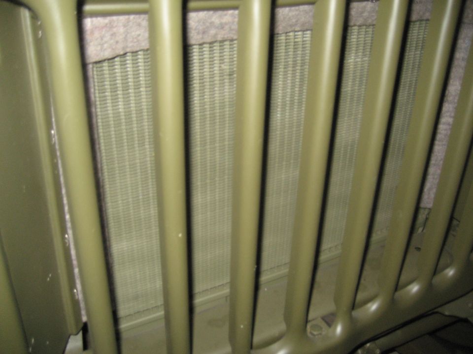 Close-up of a matte olive green vehicle grille and radiator