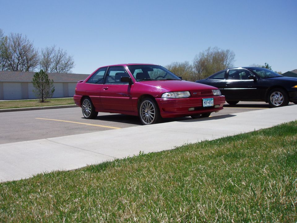 Pink two-door coupe parked next to a black sedan.