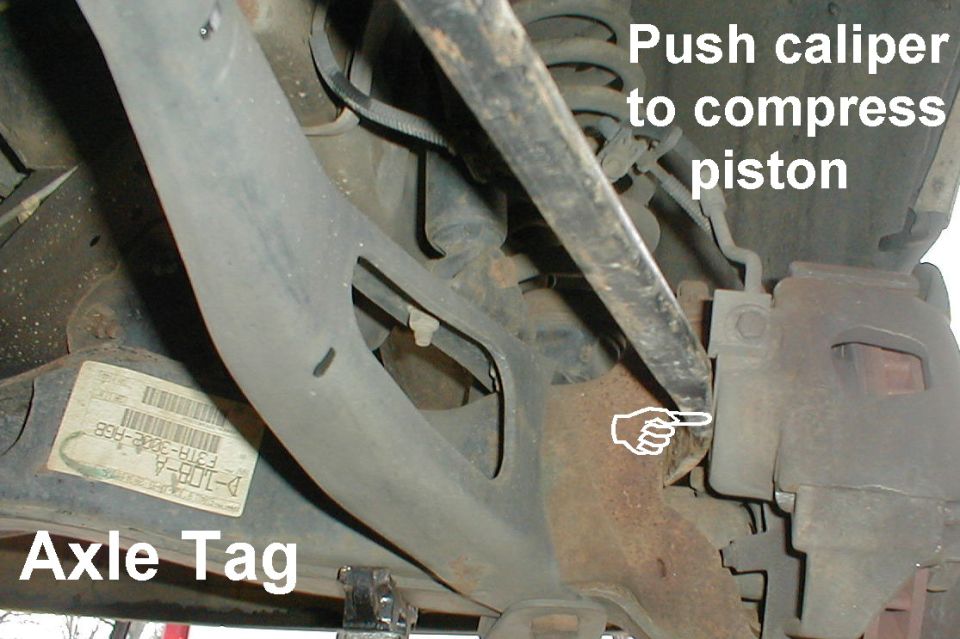 Underbody suspension and caliper with axle tag, labels to push caliper and compress piston