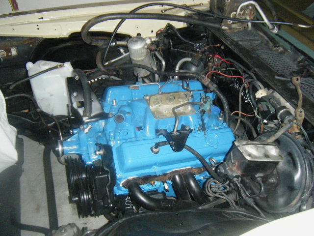 Bright blue V8 engine installed in a stripped engine bay during a rebuild