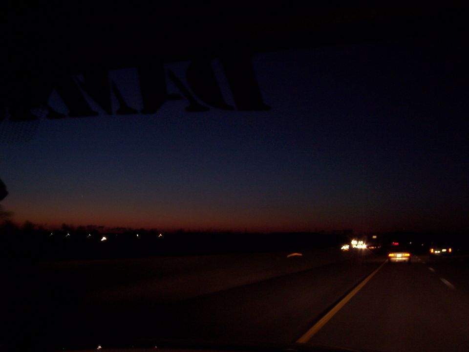 Highway at dusk with car headlights visible.