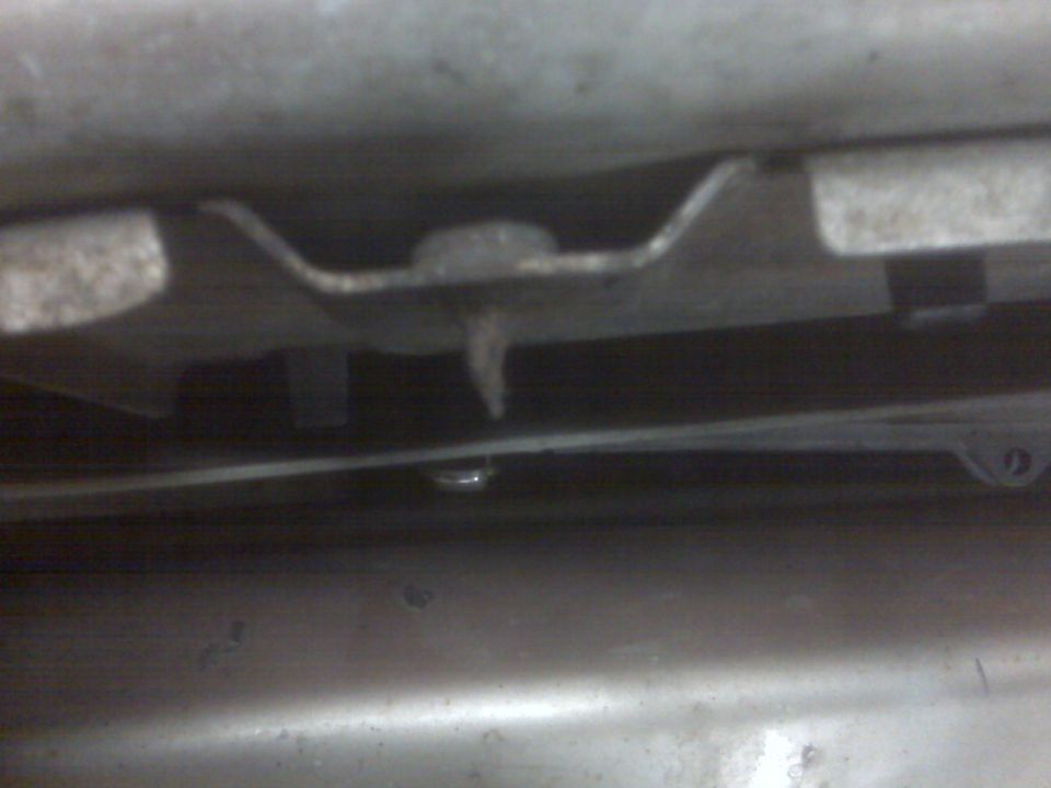 Underside of a vehicle showing a metal bracket and bolt.