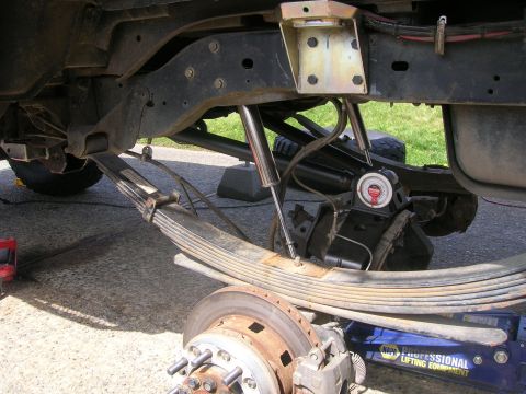 1996 Ford Bronco - Close-up view of the rear suspension of a Ford Bronco, showing the leaf springs, shocks, and brake components. A Craftsman angle gauge is a…