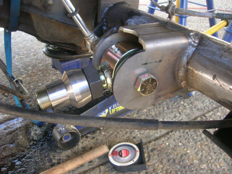 Close-up of custom vehicle suspension part with welded bracket and threaded rod end.