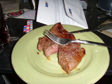 1978 Ford Bronco - A plate of sliced steak with a fork and knife rests on a table next to some documents and what appear to be military ribbons.