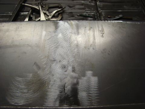 1948 Jeep Wrangler - Metal panel with welding clamps and grinder marks, likely part of a vehicle repair or fabrication process.