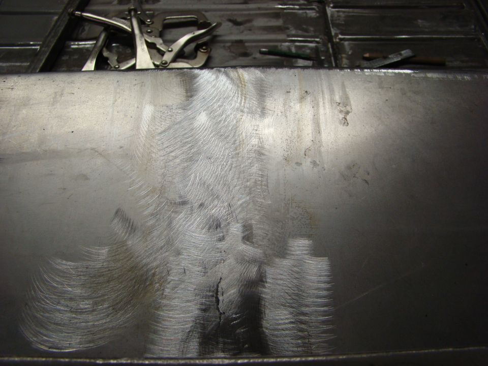 Metal panel with welding clamps and grinder marks