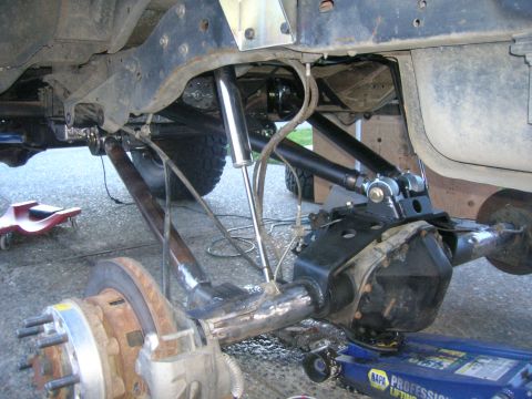 1996 Ford Bronco - The underside of a vehicle is shown with a modified suspension system including shocks, control arms, and a differential housing. A blue hy…