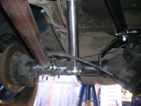 1996 Ford Bronco - The underside of a 1996 Ford Bronco showing the rear axle, suspension components, and exhaust pipe. The vehicle is supported by jack stands.