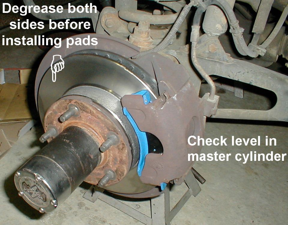 Front disc brake with blue pad on caliper, labels to degrease both sides and check master cylinder