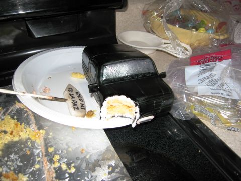 1986 Ford Bronco - A black cake designed to look like a Ford Bronco sits on a plate, with a bite taken out and cake crumbs scattered around.