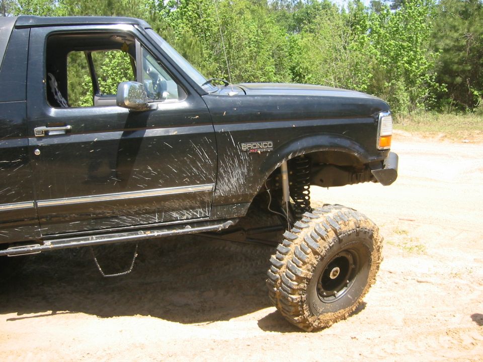 Black lifted Ford Bronco with mud splatters on the side. Bronco badge visible on fender