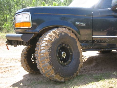 1995 Ford Bronco - Mud-splattered Ford Bronco with large off-road tires is shown from the front quarter panel.