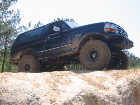 1995 Ford Bronco - This Ford Bronco is navigating a challenging off-road terrain, its capabilities on a muddy track.