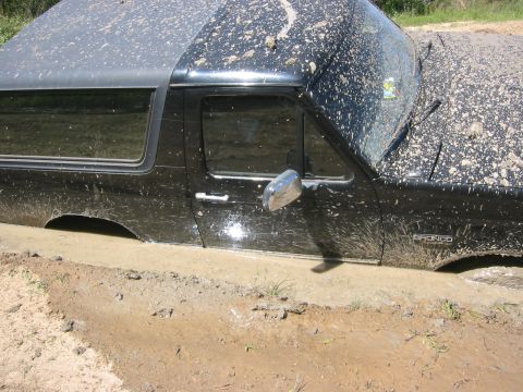 1995 Ford Bronco - Muddy 1995 Ford Bronco stuck in a ditch. The vehicle is covered in mud.