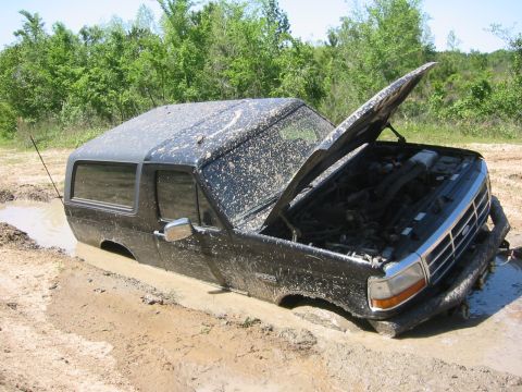 1995 Ford Bronco - Muddy 1995 Ford Bronco stuck in a ditch with its hood open.