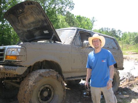1995 Ford Bronco - A man poses with a heavily mud-covered 1995 Ford Bronco after an off-road excursion.