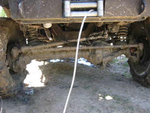 1995 Ford Bronco - Undercarriage view of a heavily muddied vehicle, showing the front axle, suspension, and a winch.