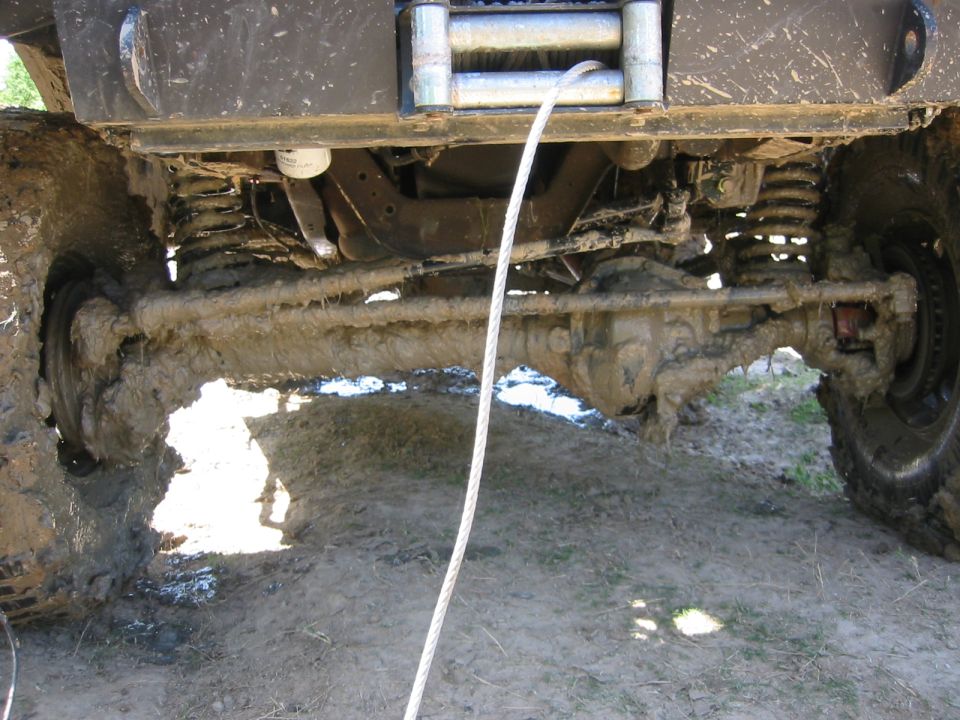 Mud-covered front axle and suspension with winch cable