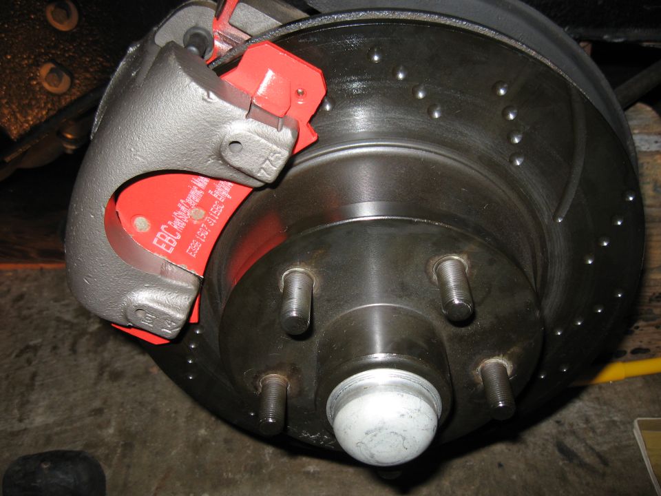 Car brake caliper with red EBC brake pads and drilled rotor