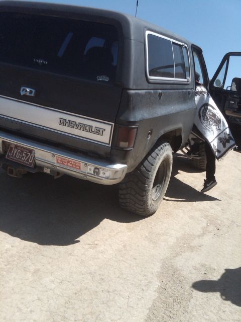 1982 Ford Bronco - A black Chevrolet SUV is parked outdoors, showing its rear end with a white stripe and visible badging.