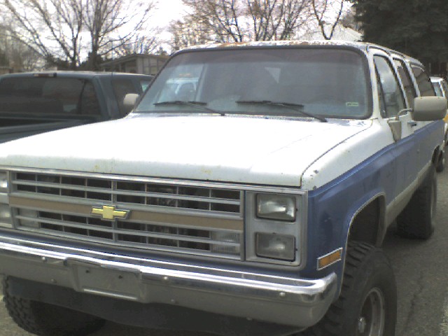 White and blue 1988 Chevrolet Suburban with chrome grille and bumper, seen from the front three-quarter angle
