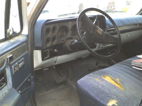 1988 Chevrolet Suburban - The interior of a 1988 Chevrolet Suburban features a blue dashboard and seat, with visible wear on the driver's seat.