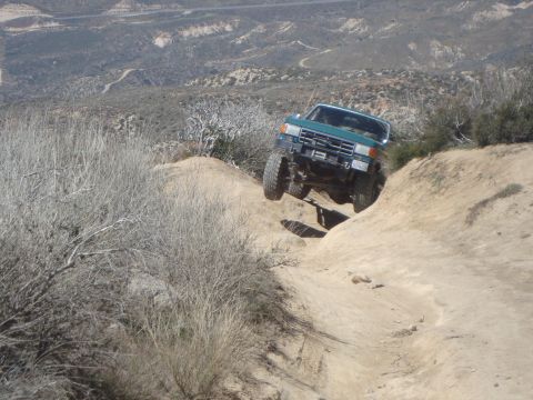 1986 Ford Bronco - This SUV navigates a challenging off-road path with steep inclines and rocky terrain.