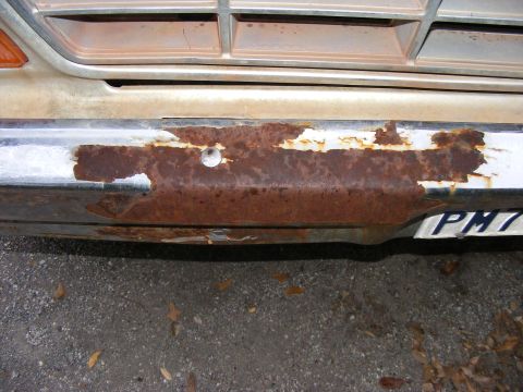 1979 Ford Bronco - The front grille and heavily rusted bumper of a vehicle are visible, with a partial license plate reading 'PM7'.
