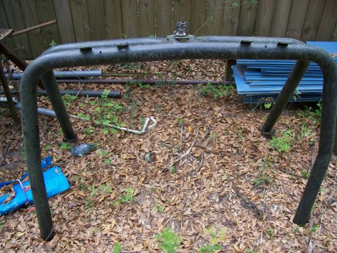 1990 Ford Bronco - A dark metal roll cage is shown outdoors, resting on a bed of fallen leaves.
