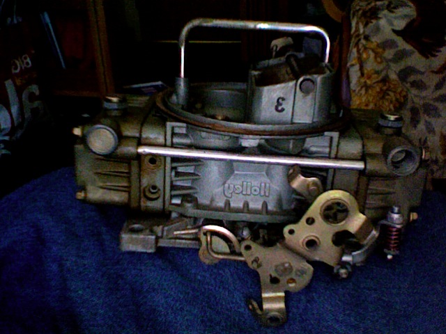 Holley carburetor with a metal handle and a number 3 on top, resting on a blue surface