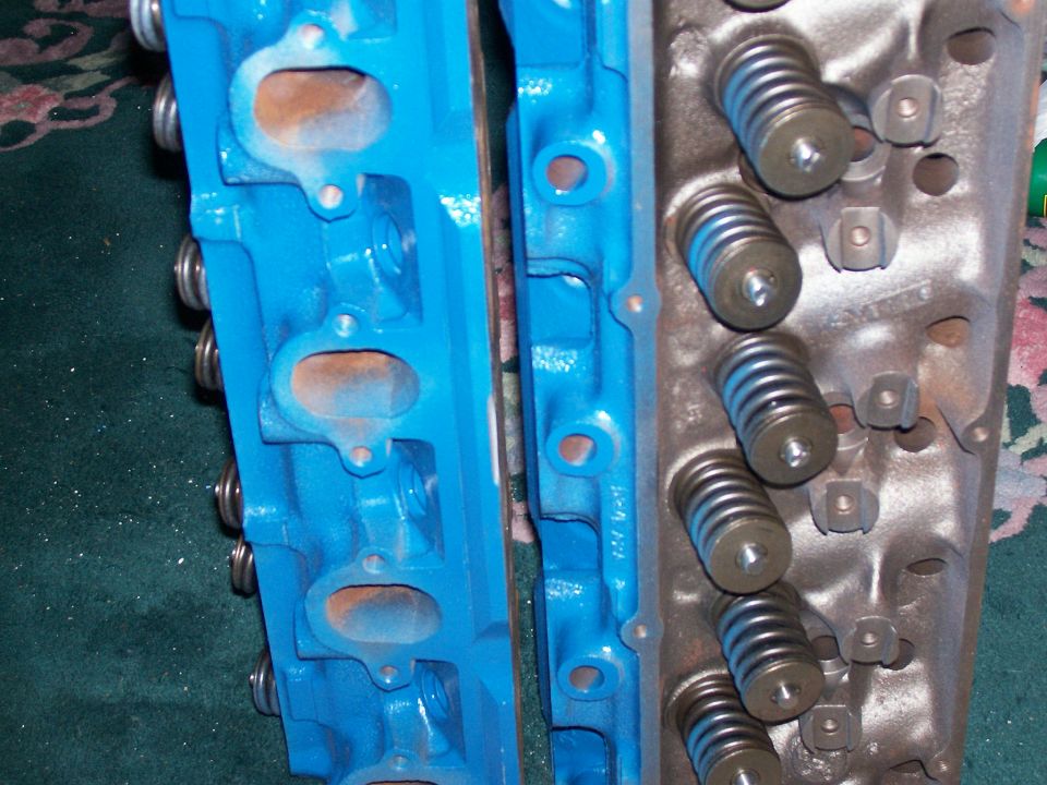 Two engine cylinder heads, one blue and one silver, with visible springs