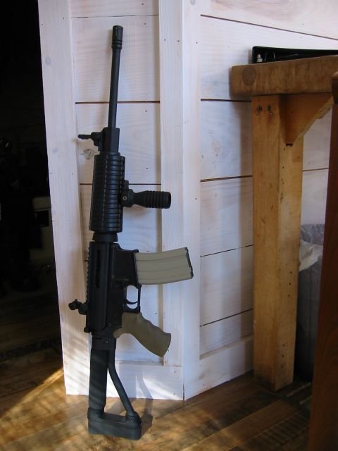 1996 Ford Bronco - Assault rifle with tan magazine and grip leaning against a white wooden wall.