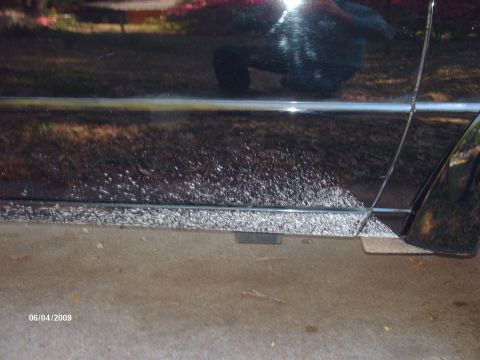 1990 Ford F-150 - Close-up of a black truck's lower body panel reveals corrosion and debris, dated 06/04/2009.