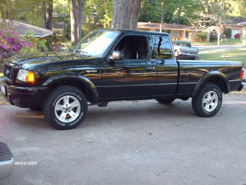 1990 Ford F-150 - This black Ford Ranger pickup truck is parked in a residential area, with another vehicle visible in the background.