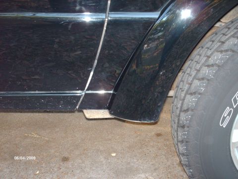 1990 Ford F-150 - A close-up view of the side of a black pickup truck, focusing on the rear fender and door seam.